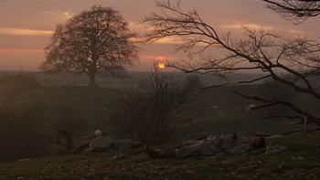 Movie still from “Royal Deceit” (1994), directed by Gabriel Axel – The sun is setting over a field with trees in the background; Extreme Wide shot, High angle