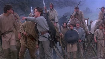Movie still from “Royal Deceit” (1994), directed by Gabriel Axel – A group of men in medieval garb marching through a field; Wide shot, Low angle