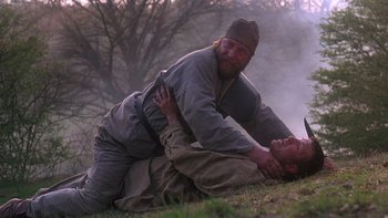 Movie still from “Royal Deceit” (1994), directed by Gabriel Axel – Two men are wrestling in the grass; Medium shot, Over the shoulder angle