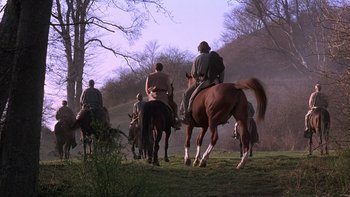 Movie still from “Royal Deceit” (1994), directed by Gabriel Axel – A group of people riding horses through a field; Wide shot, Low angle