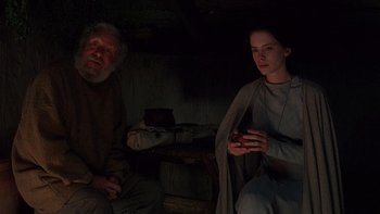 Movie still from “Royal Deceit” (1994), directed by Gabriel Axel – A man and a woman sitting next to each other in a dark room; Medium shot, High angle