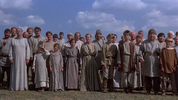 Movie still from “Royal Deceit” (1994), directed by Gabriel Axel – A large group of people standing together in a field; Wide shot, Low angle