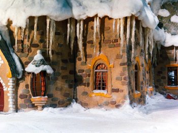 Movie still from “Rudolph and Frosty's Christmas in July” (1979), directed by Jules Bass – A building that has a lot of snow on the ground; Extreme Wide shot, Low angle