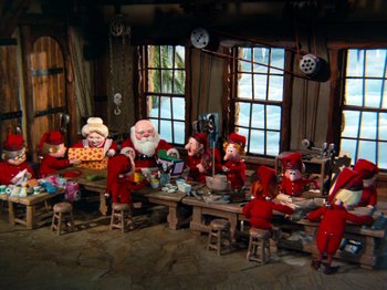 Movie still from “Rudolph and Frosty's Christmas in July” (1979), directed by Jules Bass – A group of people sitting around a table; Wide shot, High angle
