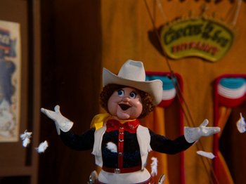 Movie still from “Rudolph and Frosty's Christmas in July” (1979), directed by Jules Bass – A toy cowboy with hands outstreched; Medium shot, Low angle