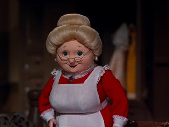 Movie still from “Rudolph and Frosty's Christmas in July” (1979), directed by Jules Bass – A doll wearing glasses and a red dress; Medium shot, Low angle