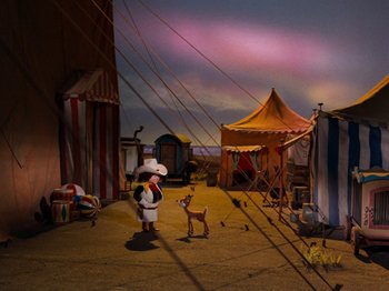 Movie still from “Rudolph and Frosty's Christmas in July” (1979), directed by Jules Bass – A person standing next to an animal on a street; Wide shot, High angle