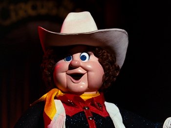 Movie still from “Rudolph and Frosty's Christmas in July” (1979), directed by Jules Bass – The face of a doll wearing a cowboy hat; Close Up shot, Low angle