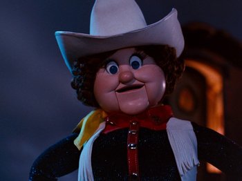 Movie still from “Rudolph and Frosty's Christmas in July” (1979), directed by Jules Bass – The face of a doll wearing a cowboy hat; Close Up shot, Low angle