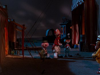 Movie still from “Rudolph and Frosty's Christmas in July” (1979), directed by Jules Bass – A group of people standing next to each other on a street; Wide shot, Low angle