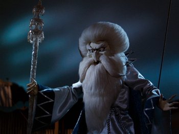 Movie still from “Rudolph and Frosty's Christmas in July” (1979), directed by Jules Bass – A man dressed as a wizard holding a staff in his hand; Medium shot, Low angle