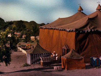 Movie still from “Rudolph and Frosty's Christmas in July” (1979), directed by Jules Bass – An old fashioned circus tent is set up in the sand; Extreme Wide shot, High angle