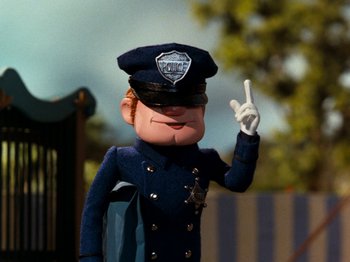 Movie still from “Rudolph and Frosty's Christmas in July” (1979), directed by Jules Bass – A toy police officer is pointing to the sky; Medium shot, Low angle