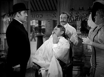 Movie still from “Ruggles of Red Gap” (1935), directed by Leo McCarey – A group of men standing around a man getting a haircut; Medium shot, Over the shoulder angle