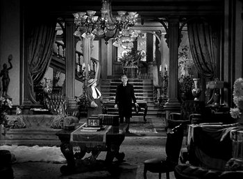 Movie still from “Ruggles of Red Gap” (1935), directed by Leo McCarey – A man sitting on a bench in front of a staircase; Wide shot, High angle