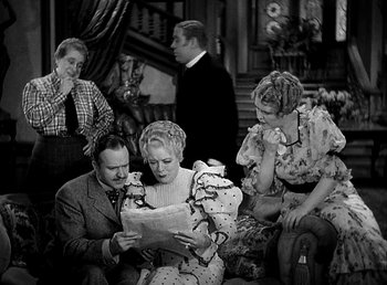 Movie still from “Ruggles of Red Gap” (1935), directed by Leo McCarey – A group of people gathered around a woman reading a paper; Medium shot, High angle