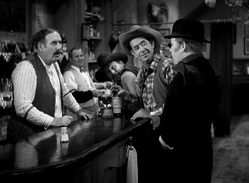 Movie still from “Ruggles of Red Gap” (1935), directed by Leo McCarey – A black and white photo of a group of men at a bar; Medium shot, Over the shoulder angle
