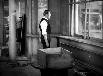 Movie still from “Ruggles of Red Gap” (1935), directed by Leo McCarey – A black and white photo of a man standing in front of a box; Medium shot, Over the shoulder angle