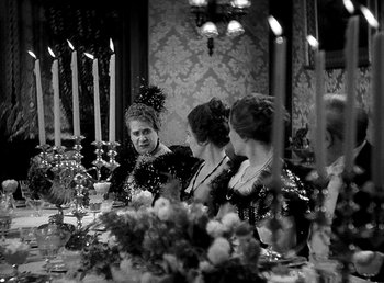 Movie still from “Ruggles of Red Gap” (1935), directed by Leo McCarey – A group of people sitting at a table with candles; Medium shot, High angle