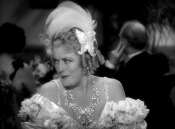 Movie still from “Ruggles of Red Gap” (1935), directed by Leo McCarey – An older woman in a dress and a feather headdress; Close Up shot, Over the shoulder angle