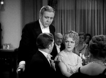 Movie still from “Ruggles of Red Gap” (1935), directed by Leo McCarey – An old photo of a man and a woman at a party; Medium shot, Over the shoulder angle