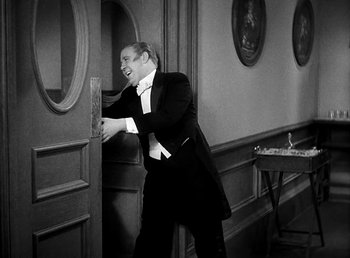Movie still from “Ruggles of Red Gap” (1935), directed by Leo McCarey – A black and white photo of a man opening a door; Medium shot, High angle
