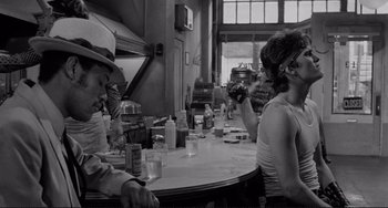 Movie still from “Rumble Fish” (1983), directed by Francis Ford Coppola – A group of people sitting at a table with drinks; Medium shot, Over the shoulder angle