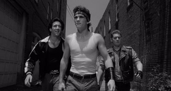 Movie still from “Rumble Fish” (1983), directed by Francis Ford Coppola – A group of young men standing next to each other on a street; Medium shot, Low angle