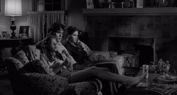 Movie still from “Rumble Fish” (1983), directed by Francis Ford Coppola – Three people sitting on a couch watching television; Wide shot, High angle
