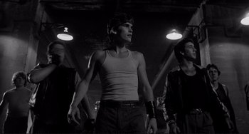 Movie still from “Rumble Fish” (1983), directed by Francis Ford Coppola – A group of young men standing next to each other in a building; Medium shot, Low angle