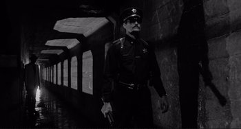 Movie still from “Rumble Fish” (1983), directed by Francis Ford Coppola – A man in uniform holding a gun in a tunnel; Wide shot, Low angle