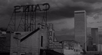 Movie still from “Rumble Fish” (1983), directed by Francis Ford Coppola – An old neon sign on the side of a building; Extreme Wide shot, Low angle