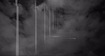 Movie still from “Rumble Fish” (1983), directed by Francis Ford Coppola – A black and white photo of some poles in the fog; Extreme Wide shot, High angle