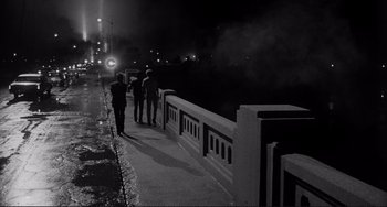 Movie still from “Rumble Fish” (1983), directed by Francis Ford Coppola – A group of people standing next to a railing on a bridge; Wide shot, High angle