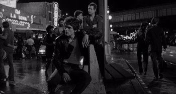 Movie still from “Rumble Fish” (1983), directed by Francis Ford Coppola – A black and white photo of a group of men sitting on a bench; Medium shot, Low angle