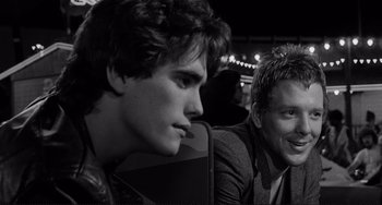 Movie still from “Rumble Fish” (1983), directed by Francis Ford Coppola – Two young men sitting next to each other in front of lights; Close Up shot, Over the shoulder angle