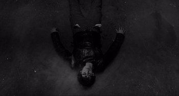 Movie still from “Rumble Fish” (1983), directed by Francis Ford Coppola – A man laying on the ground in the middle of the night; Medium shot, Overhead angle