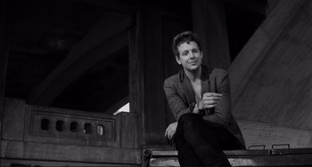 Movie still from “Rumble Fish” (1983), directed by Francis Ford Coppola – A man sitting on top of a wooden bench; Medium shot, Low angle