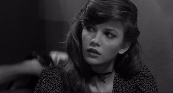 Movie still from “Rumble Fish” (1983), directed by Francis Ford Coppola – A woman with long brown hair wearing a black and white shirt; Close Up shot, Over the shoulder angle