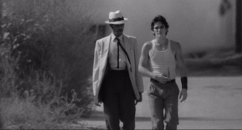 Movie still from “Rumble Fish” (1983), directed by Francis Ford Coppola – A man and a man walking down a street; Medium shot, Over the shoulder angle