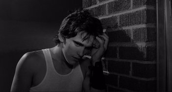 Movie still from “Rumble Fish” (1983), directed by Francis Ford Coppola – Black and white photograph of a man leaning against a brick wall; Close Up shot, Low angle