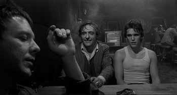 Movie still from “Rumble Fish” (1983), directed by Francis Ford Coppola – A man sitting at a table with a cigarette in his hand; Medium shot, Over the shoulder angle