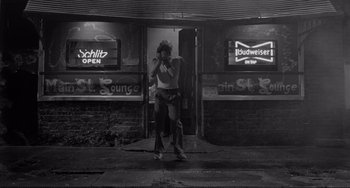Movie still from “Rumble Fish” (1983), directed by Francis Ford Coppola – A man standing in front of a building on a cell phone; Wide shot, Low angle