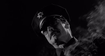 Movie still from “Rumble Fish” (1983), directed by Francis Ford Coppola – A black and white photo of a man in a police uniform; Close Up shot, Low angle
