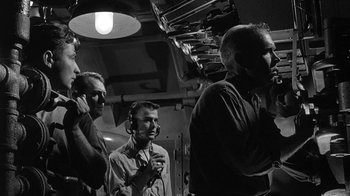 Movie still from “Run Silent Run Deep” (1958), directed by Robert Wise – A group of men standing next to each other on a boat; Medium shot, Low angle