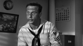 Movie still from “Run Silent Run Deep” (1958), directed by Robert Wise – Black and white photograph of a man in a sailor's uniform; Close Up shot, Low angle
