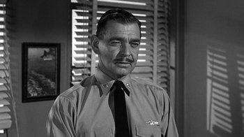 Movie still from “Run Silent Run Deep” (1958), directed by Robert Wise – An older man wearing a black tie and a white dress shirt; Close Up shot, Over the shoulder angle