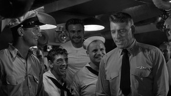 Movie still from “Run Silent Run Deep” (1958), directed by Robert Wise – A black and white photo of a group of sailors; Medium shot, Over the shoulder angle