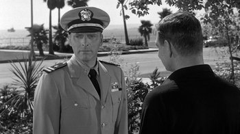 Movie still from “Run Silent Run Deep” (1958), directed by Robert Wise – A man in a uniform talking to another man; Medium shot, Over the shoulder angle