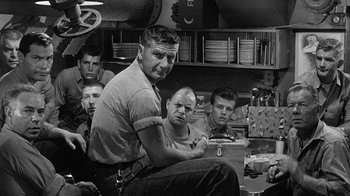 Movie still from “Run Silent Run Deep” (1958), directed by Robert Wise – A group of men sitting in front of each other in a room; Medium shot, Over the shoulder angle